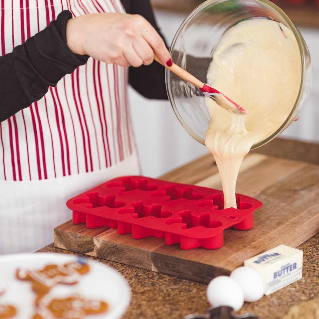 Adult pouring batter into gingerbread man mold