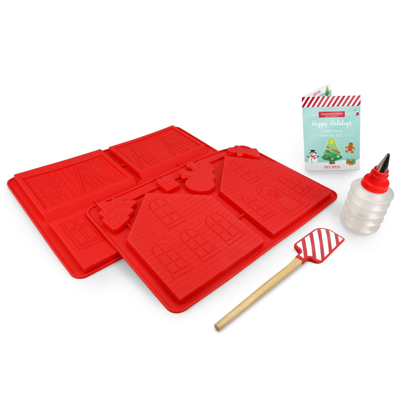 Out of box image of Make Your Own Gingerbread House Set including: 2 silicone gingerbread house molds, 1 striped silicone spatula, 1 frosting bottle with tip, recipes and building instructions.