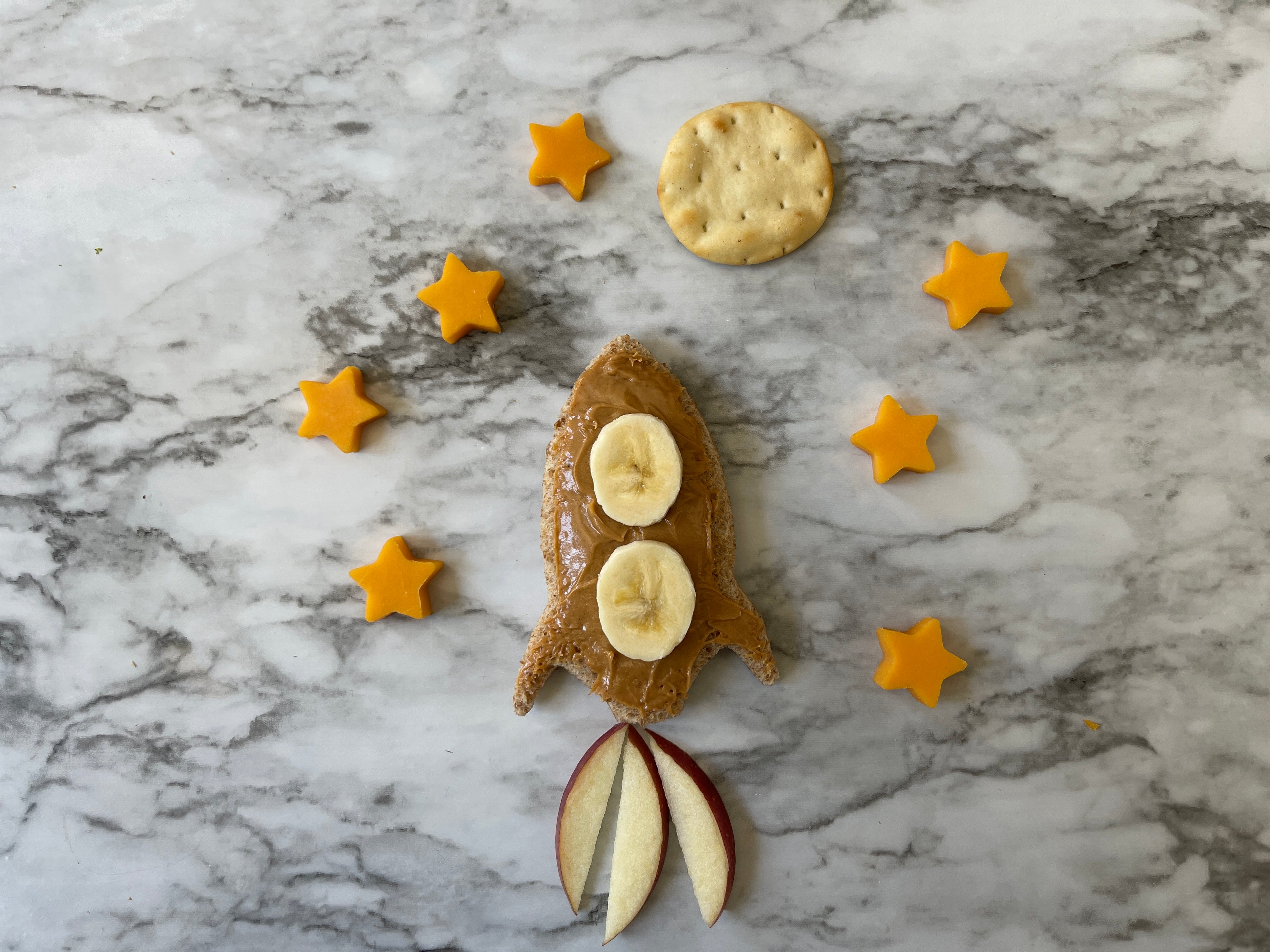 Lifestyle image of a rocket shaped sandwich surrounded by star shaped cheese