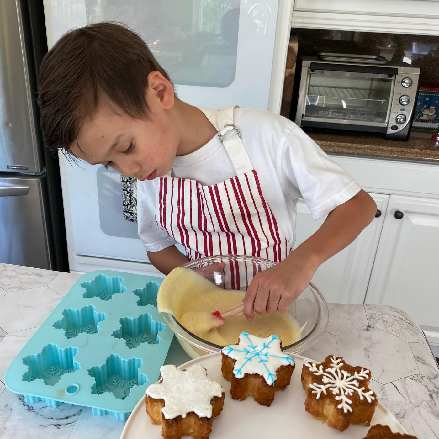 Lifestyle image of a child using the Image of Winter Wonderland Snowflake Cupcake Mold  to bake cupcakes