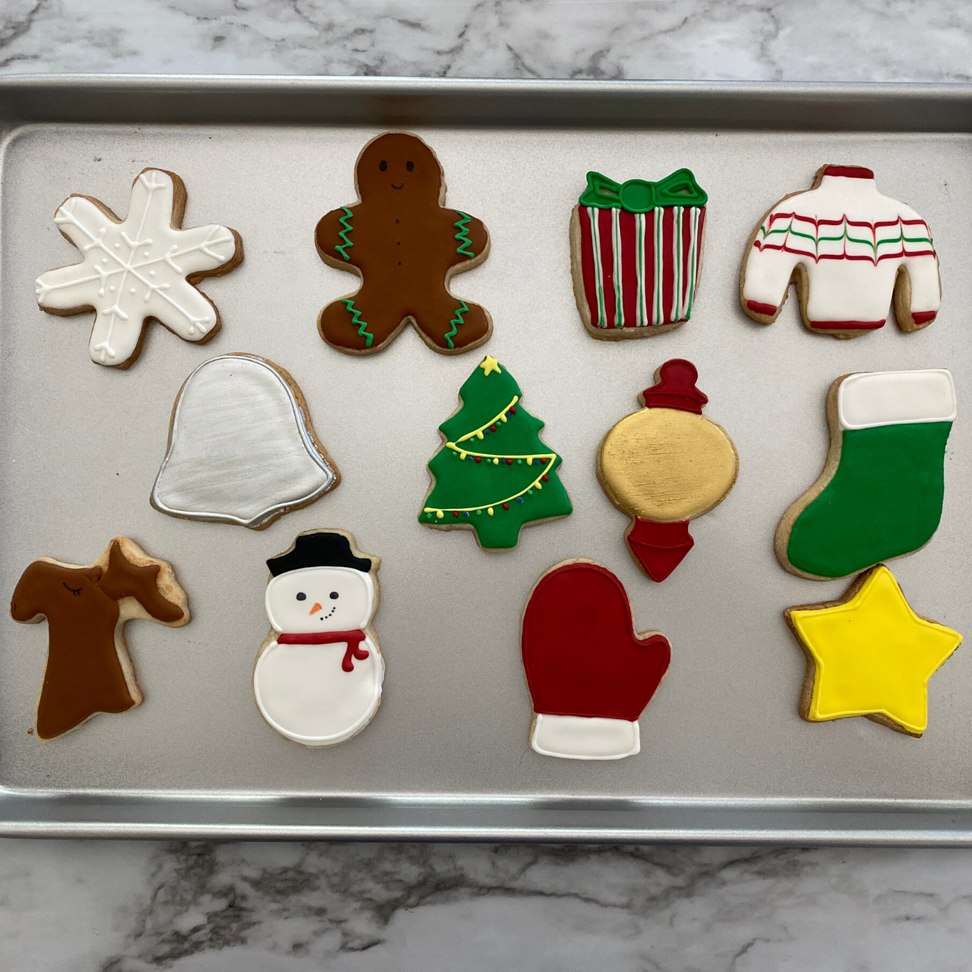 Lifestyle image of completed winter wonderland cookies including a snowman, Christmas tree, snowflake, and more.