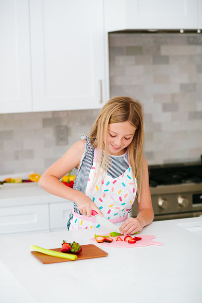 Lifestyle image of a girl using the Kid Safe Cutting Board and Serrated Knife Set Pink Unicorn