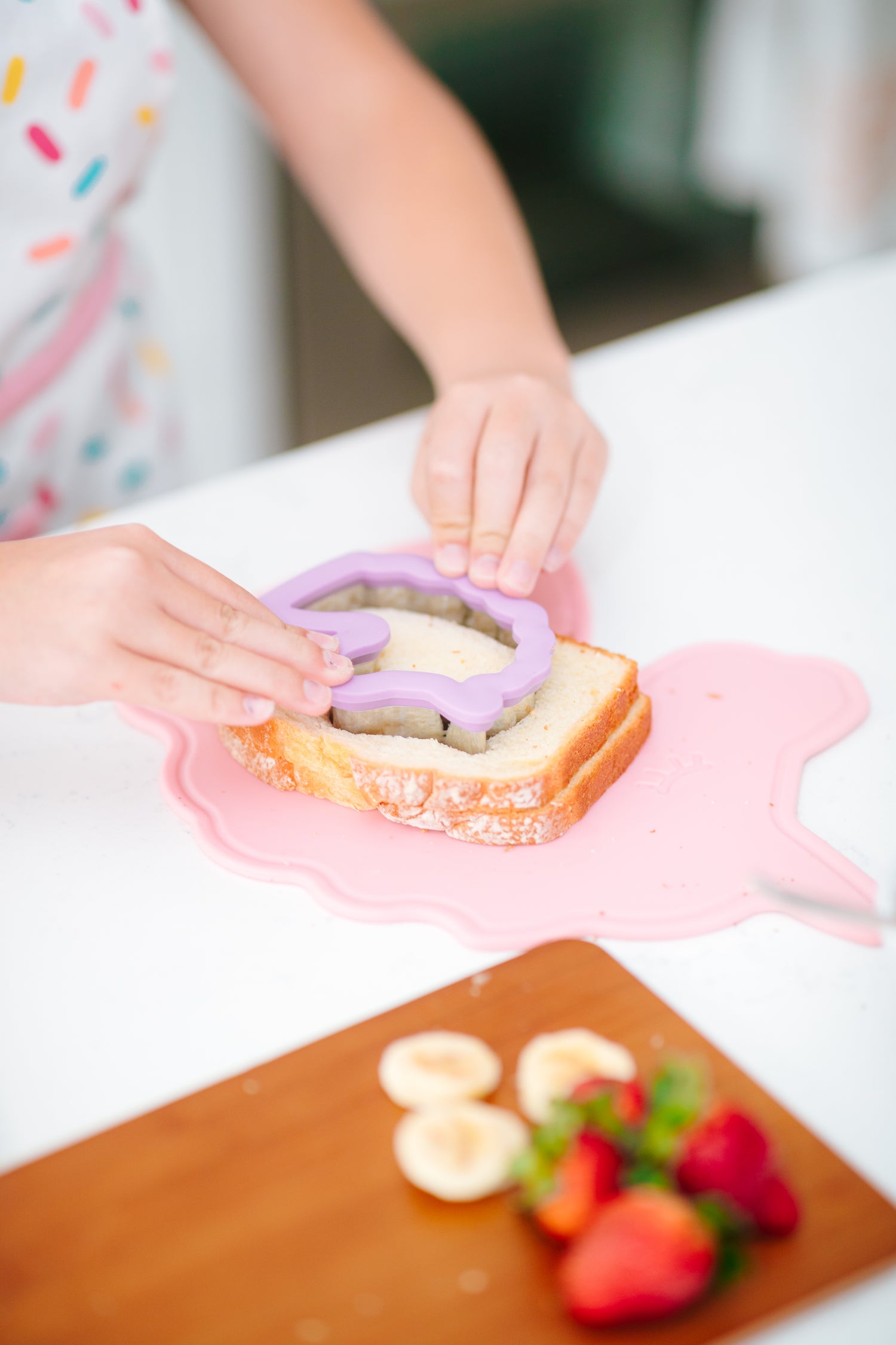 Lifestyle image of a person cutting out a unicorn shaped sandwich on a unicorn shaped cutting board