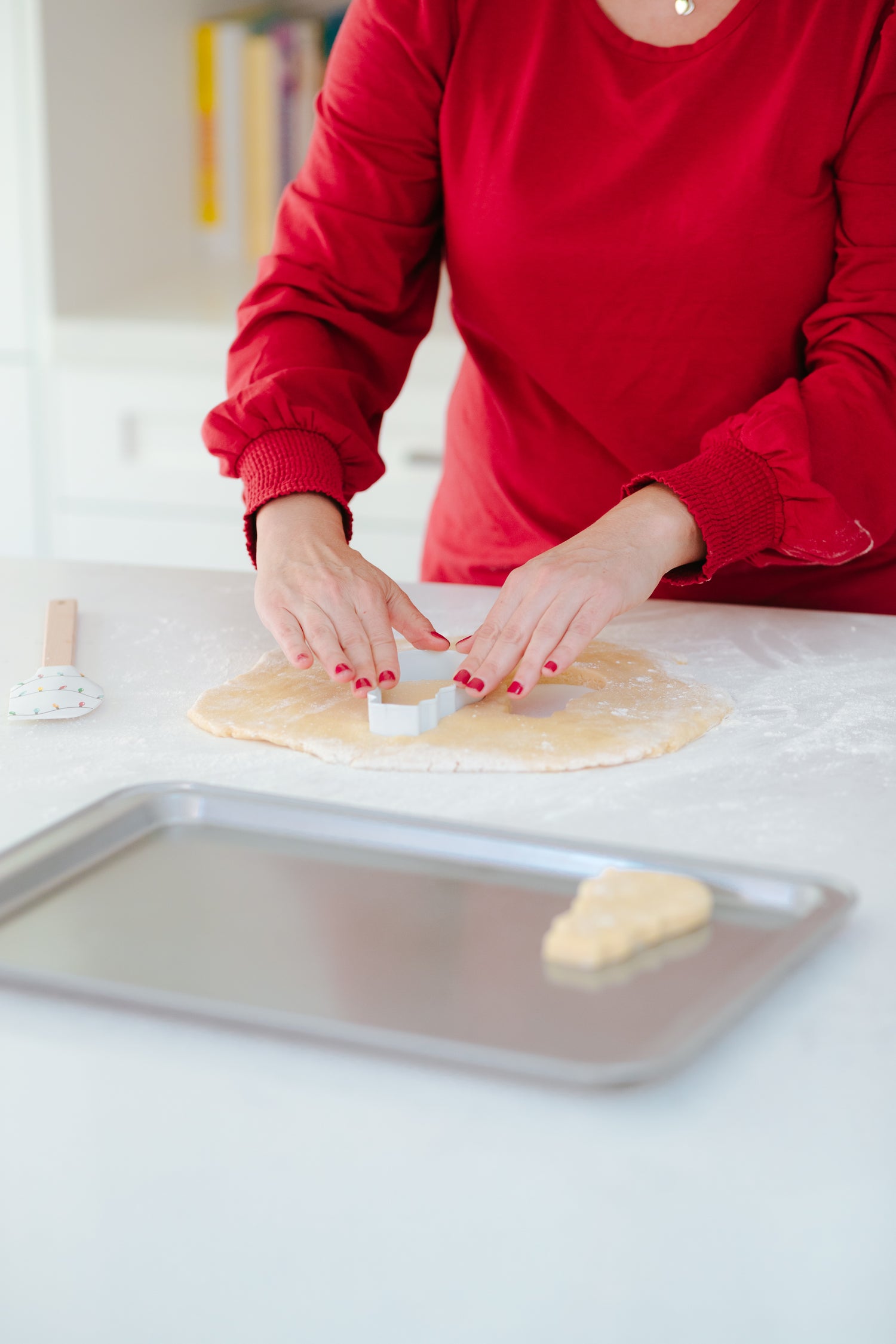 Lifestyle image of a person using the snowman cookie cutter to cut out cookies 