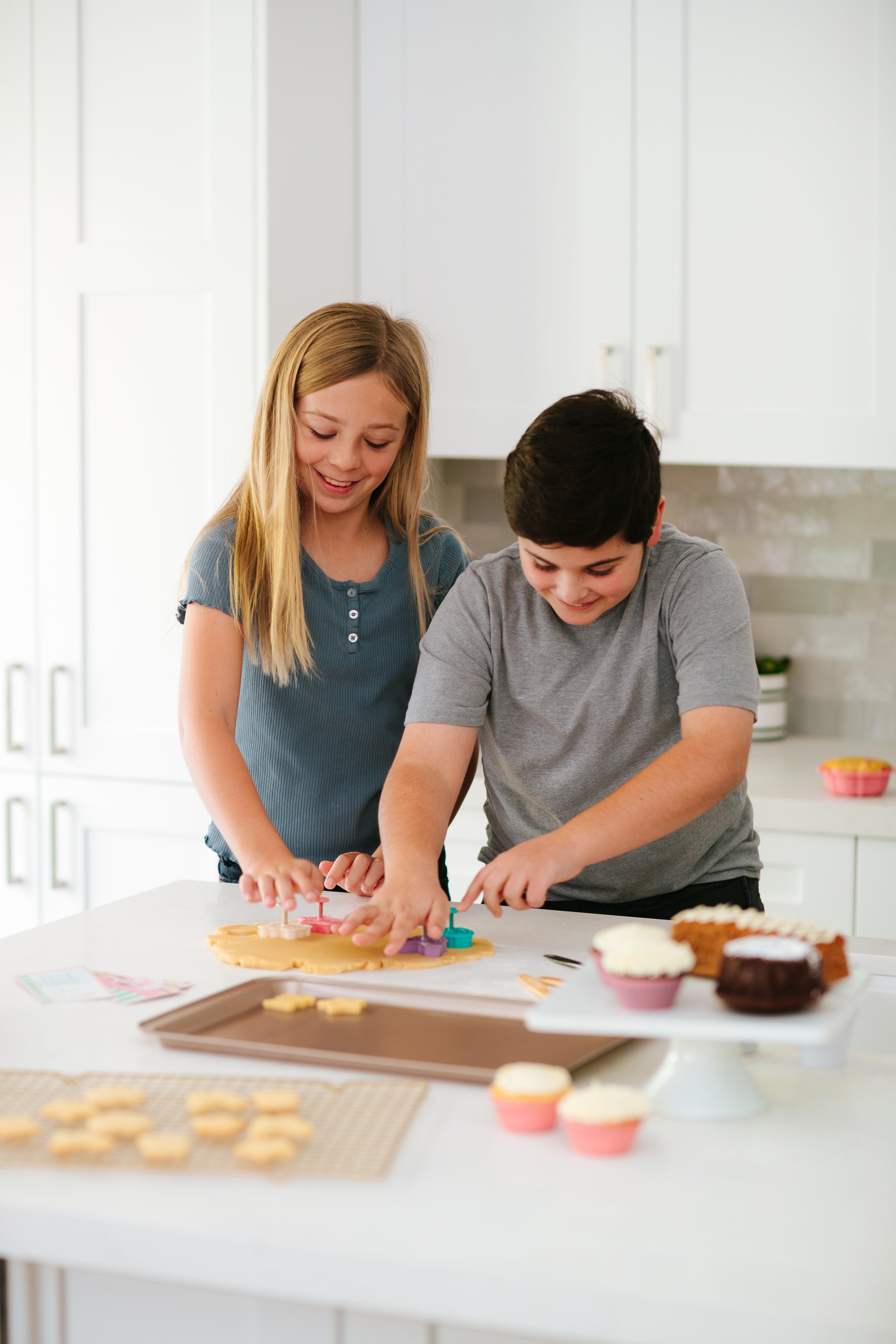 Lifestyle image of a boy and a girl icing cupcakes