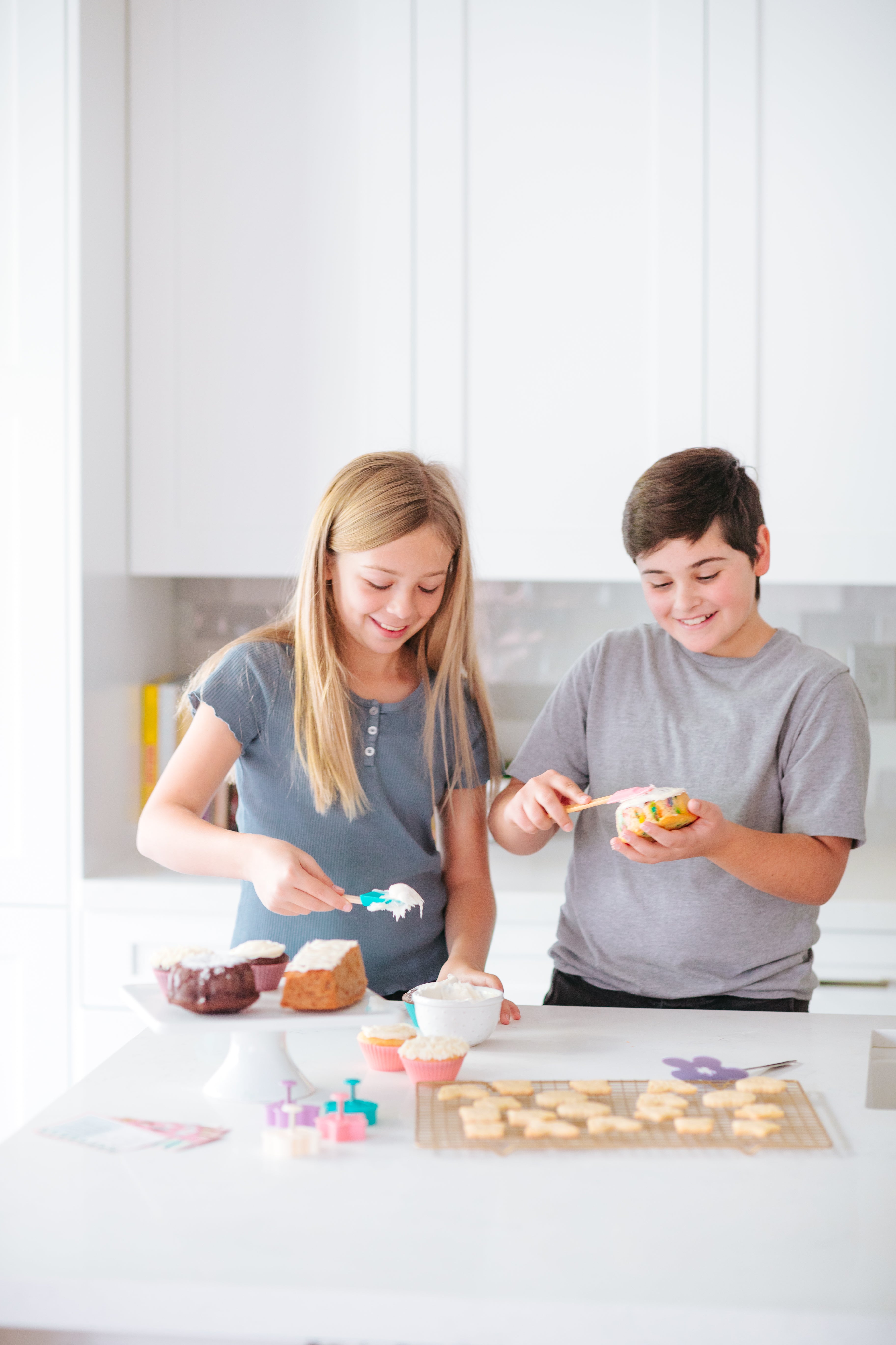 Lifestyle image of a boy and a girl icing cupcakes