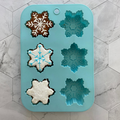 Lifestyle image of Winter Wonderland Snowflake Cupcake Mold with three decorated snowflake cupcakes 