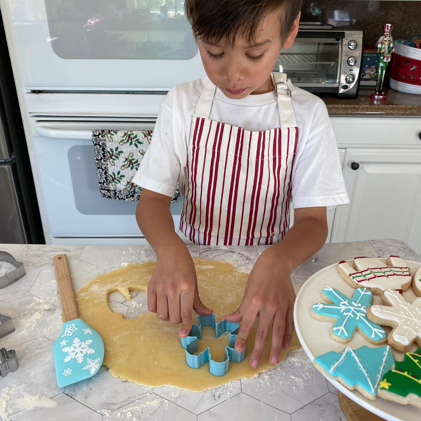 Lifestyle image of a child using the snowflake cookie cutter to cut out cookies