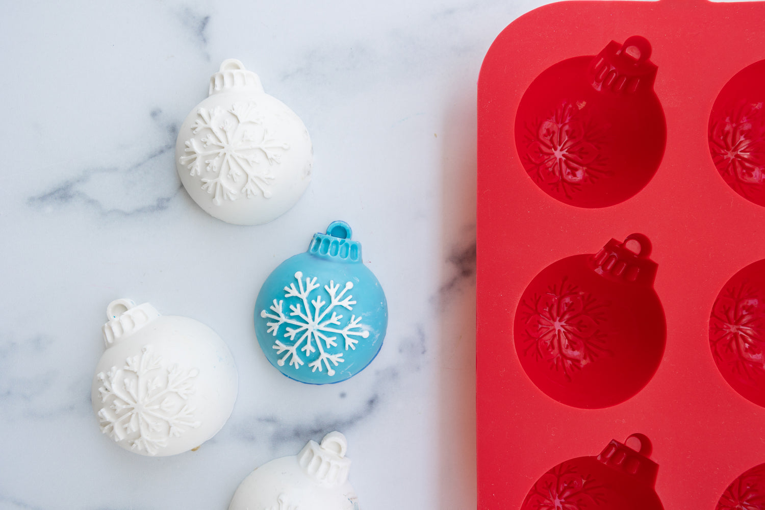 lifestyle image of three holiday ornament cupcakes next to the  Winter Wonderland Holiday Ornament Cupcake Mold