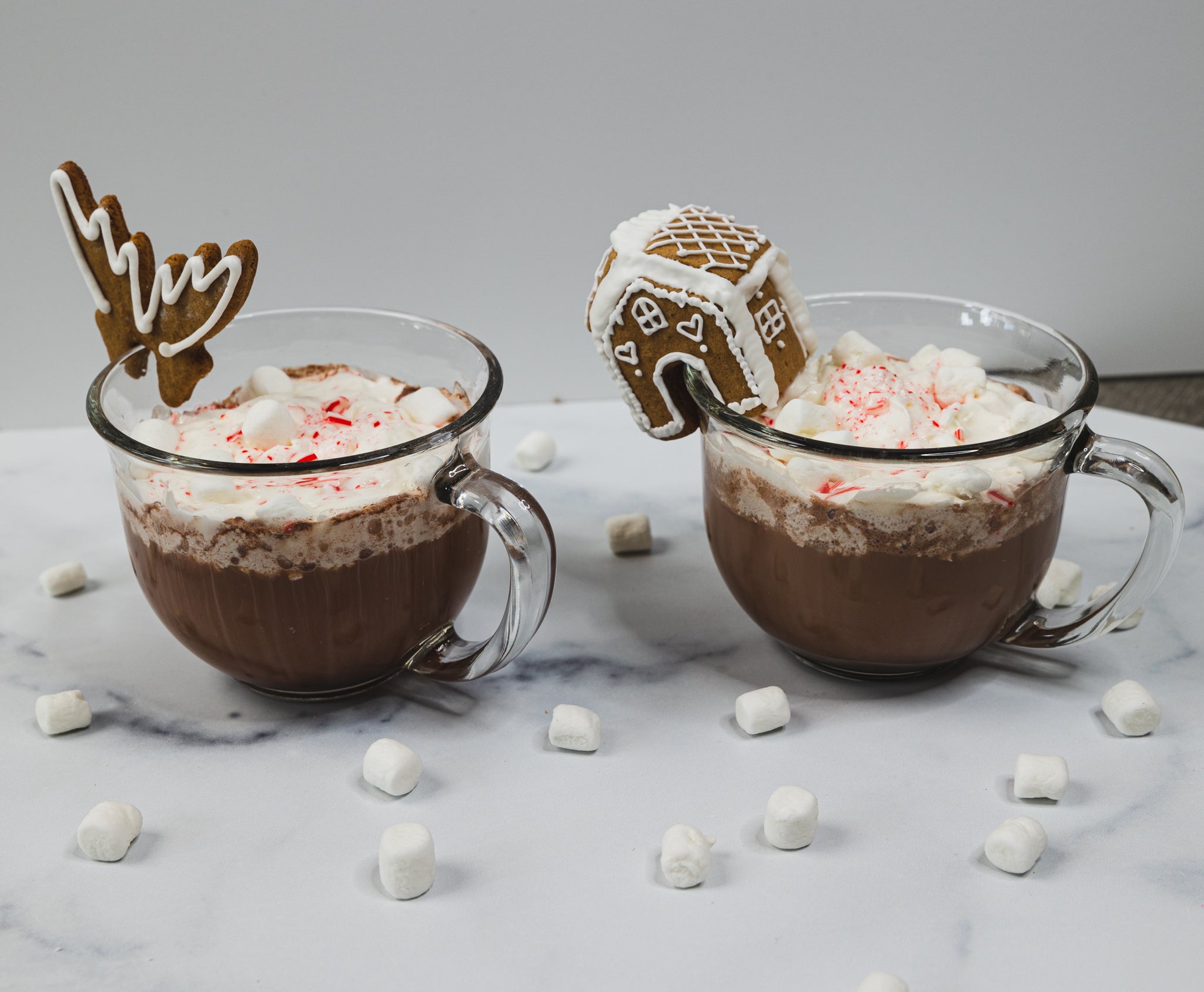Lifestyle image of two hot chocolate cups with mug huggers on them. 