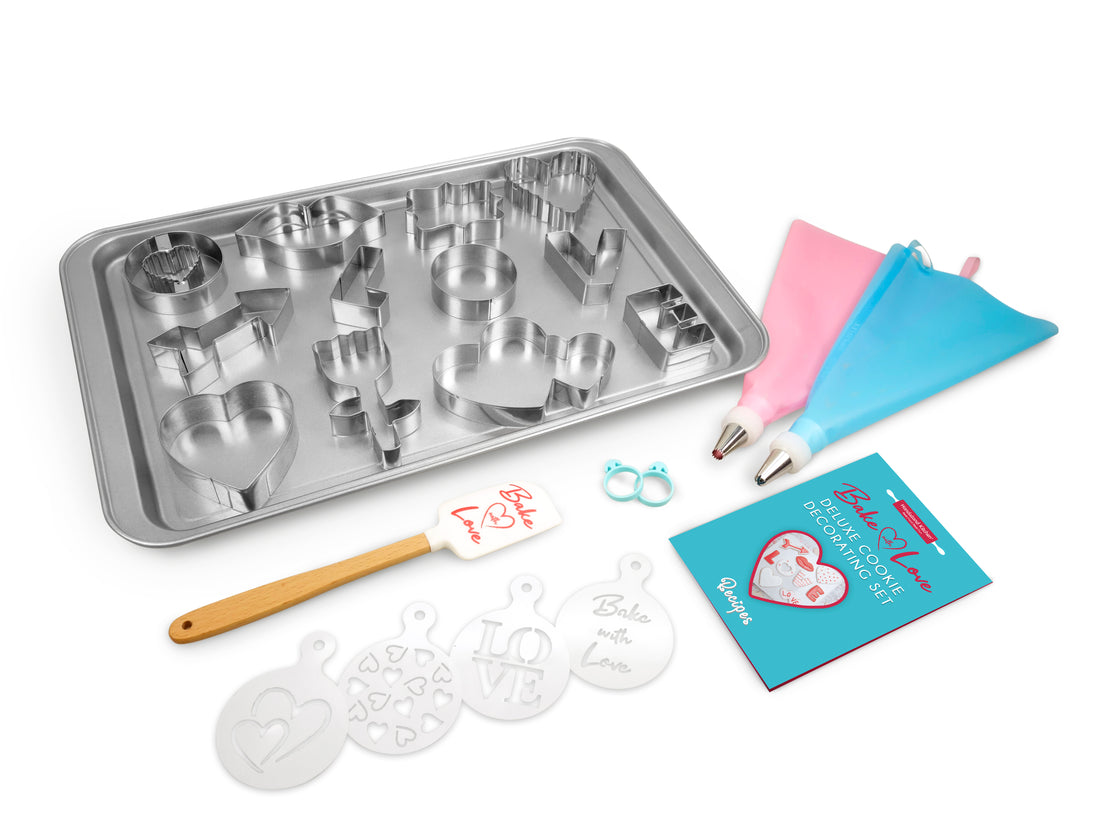 Out of box image of Bake with Love Deluxe Cookie Decorating Set containing: 1 large non-stick baking sheet, 12 stainless steel cookie  cutters (L-O-V-E, flower, arrow, lips, gift, and various heart shapes),  1 spatula, 4 decorating stencils, 2 frosting bags, 2 frosting couplers  with rings, 2 frosting tips, 2 frosting bag ties and recipes.