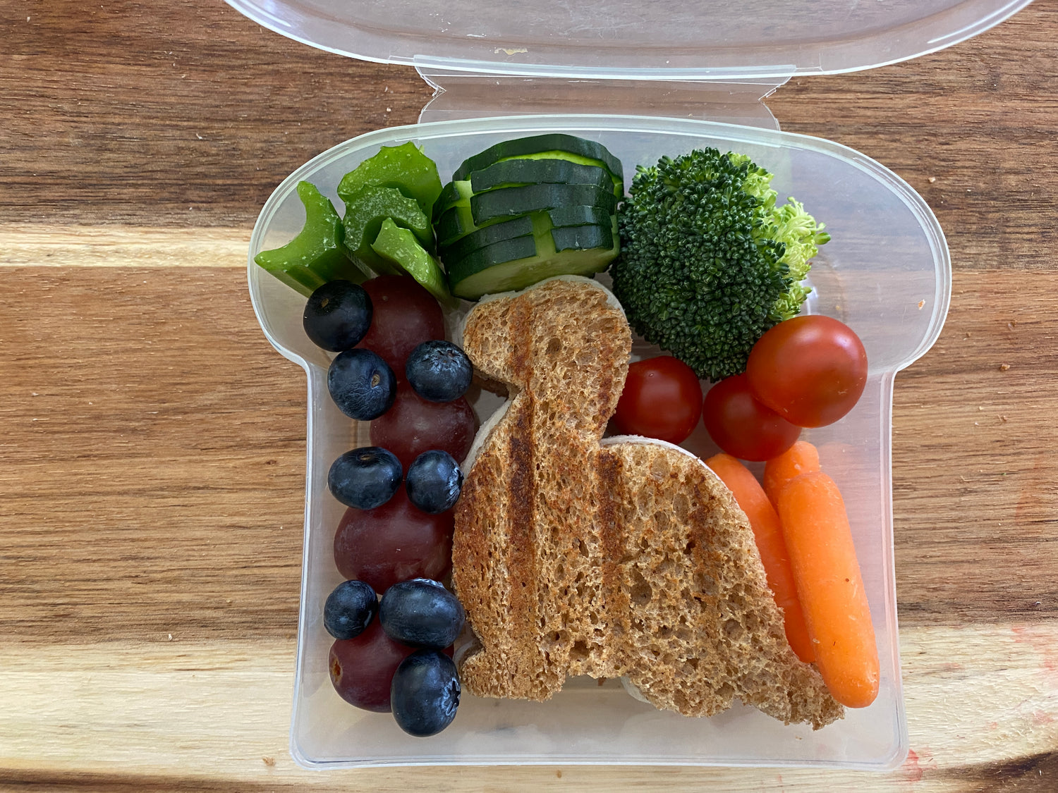 Lifestyle image of a dinosaur shaped sandwich and vegetables in the lunch box 