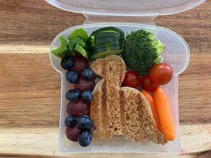 Lifestyle image of a dinosaur shaped sandwich and vegetables in the lunch box 