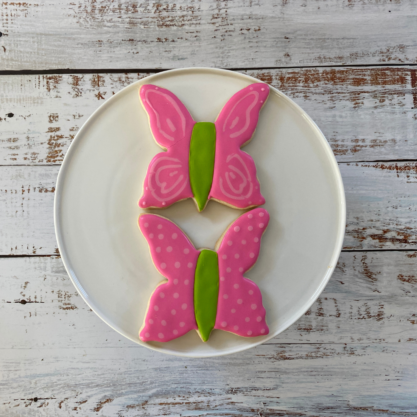Lifestyle image of two decorated butterfly shaped cookies.