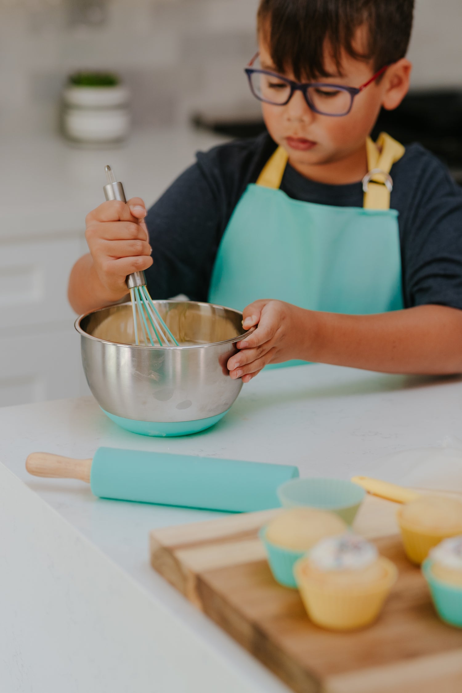 lifestyle image of young boy using the Classic Kids Baking Set to whisk cupcake batter