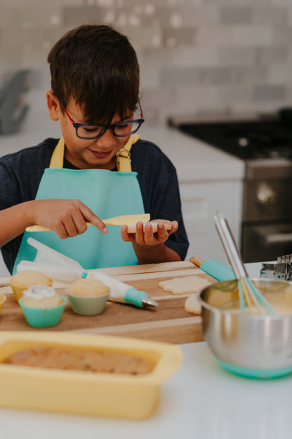 lifestyle image of young boy using the Classic Kids Baking Set to frost cookies