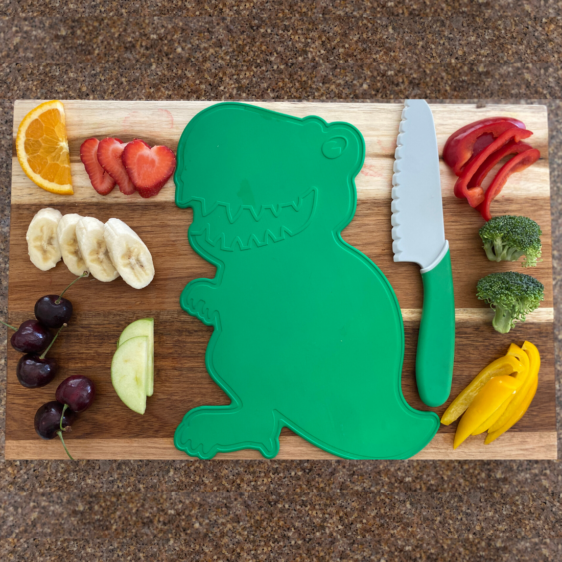 Lifestyle image of Dinosaur Cutting Board and Kid Safe Knife Set used to slice fruits and vegetables