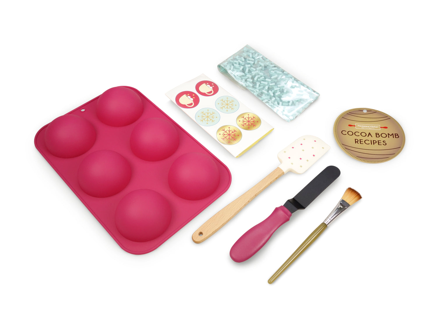 Out of box image of Make your own Hot Cocoa Bomb set including:1 silicone mold to make 3 cocoa bombs, 1 spatula, 1 brush, 1 scraper,  gift bags, stickers and recipes, plus QR code link to exclusive recipes and videos.