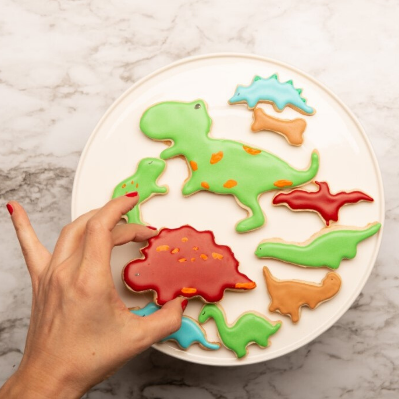 Frosted and decorated dinosaur shaped cookies made using Dinosaur Shape 10 Piece Kids Cookie Cutter Set 