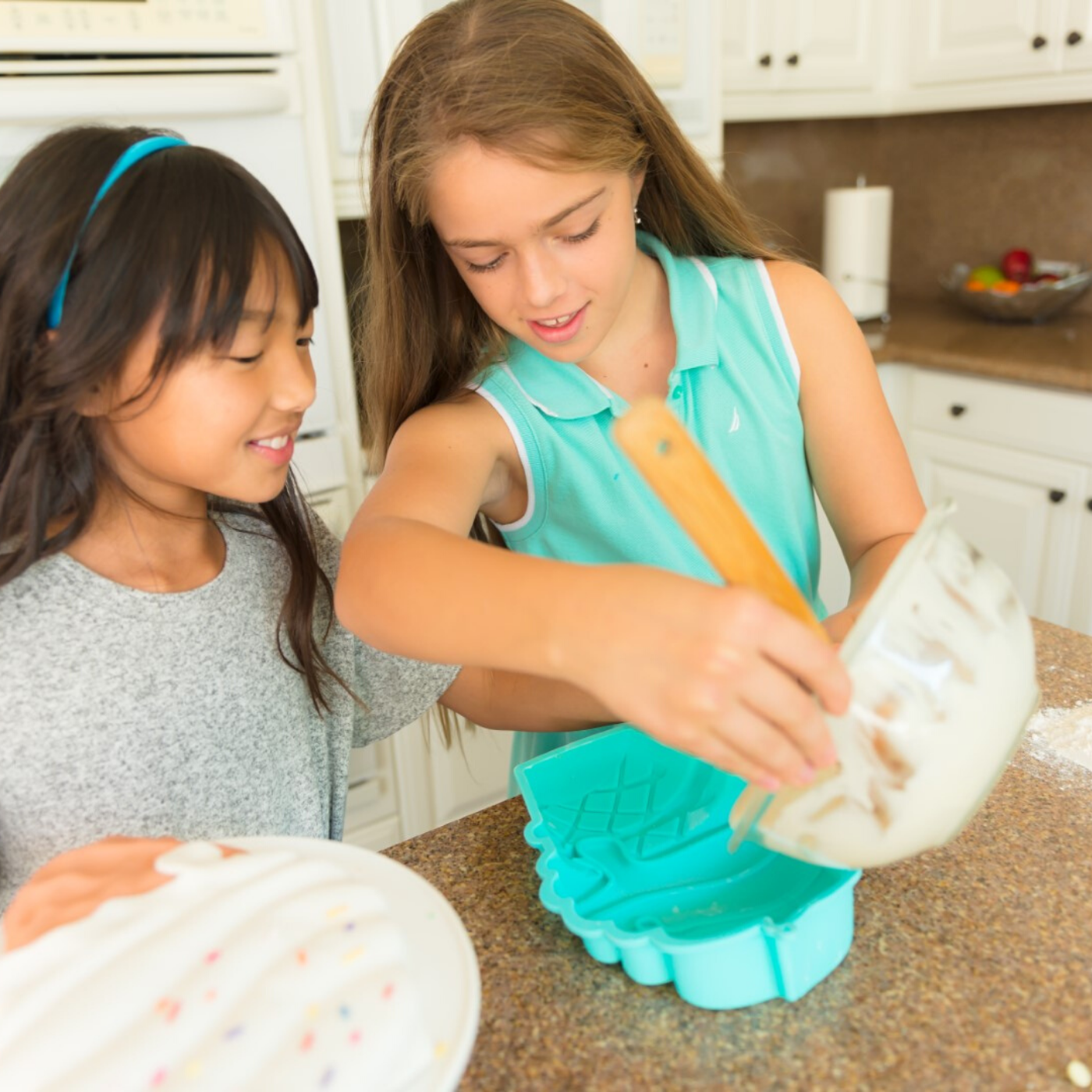 Lifestyle photo of children pouring batter into the Ice cream cone shaped cake mold.