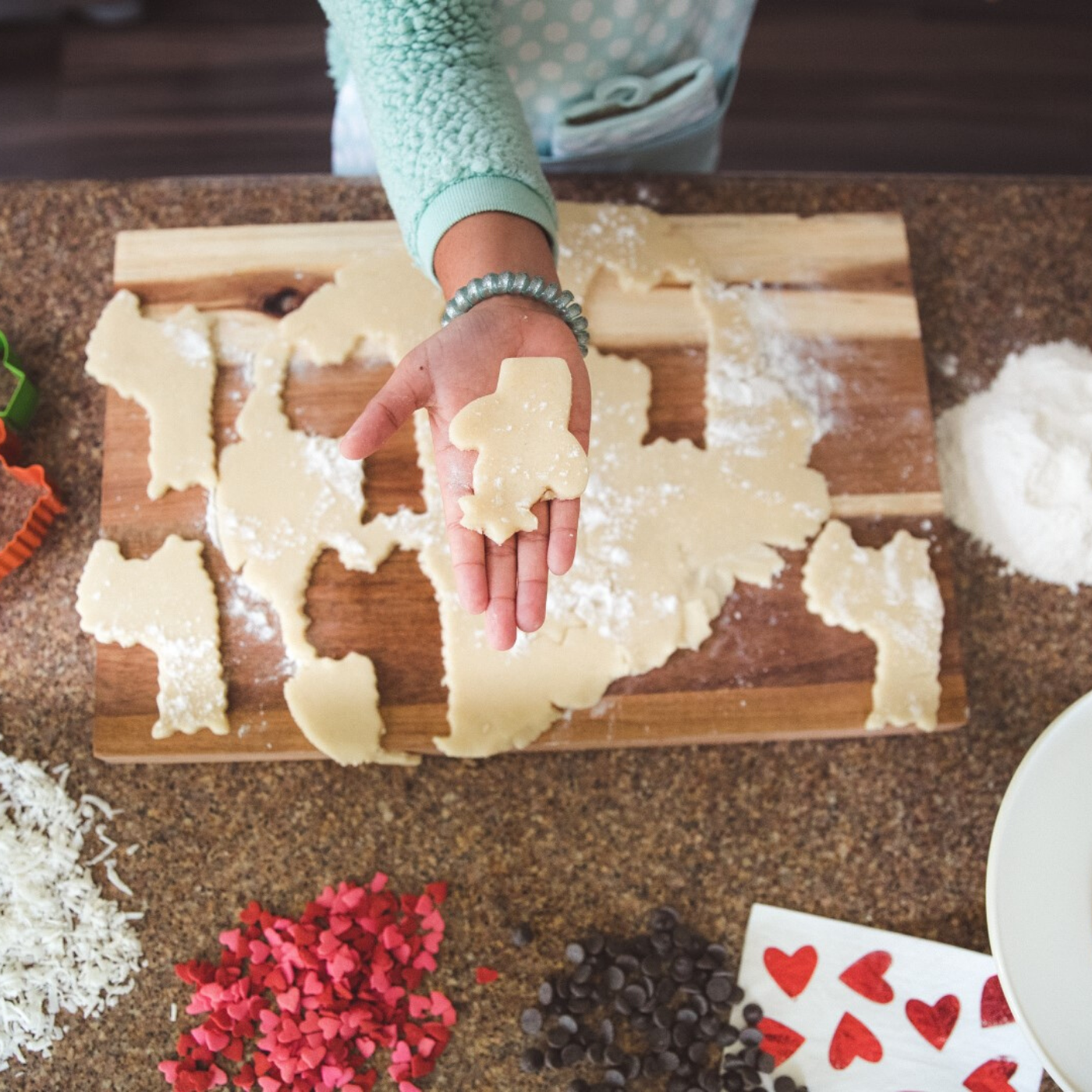 Lifestyle photo of hild holing a cut out of cactus shaped cookie dough made with Llama Love and Cactus Shaped Cookie Cutter 2 Pack Set