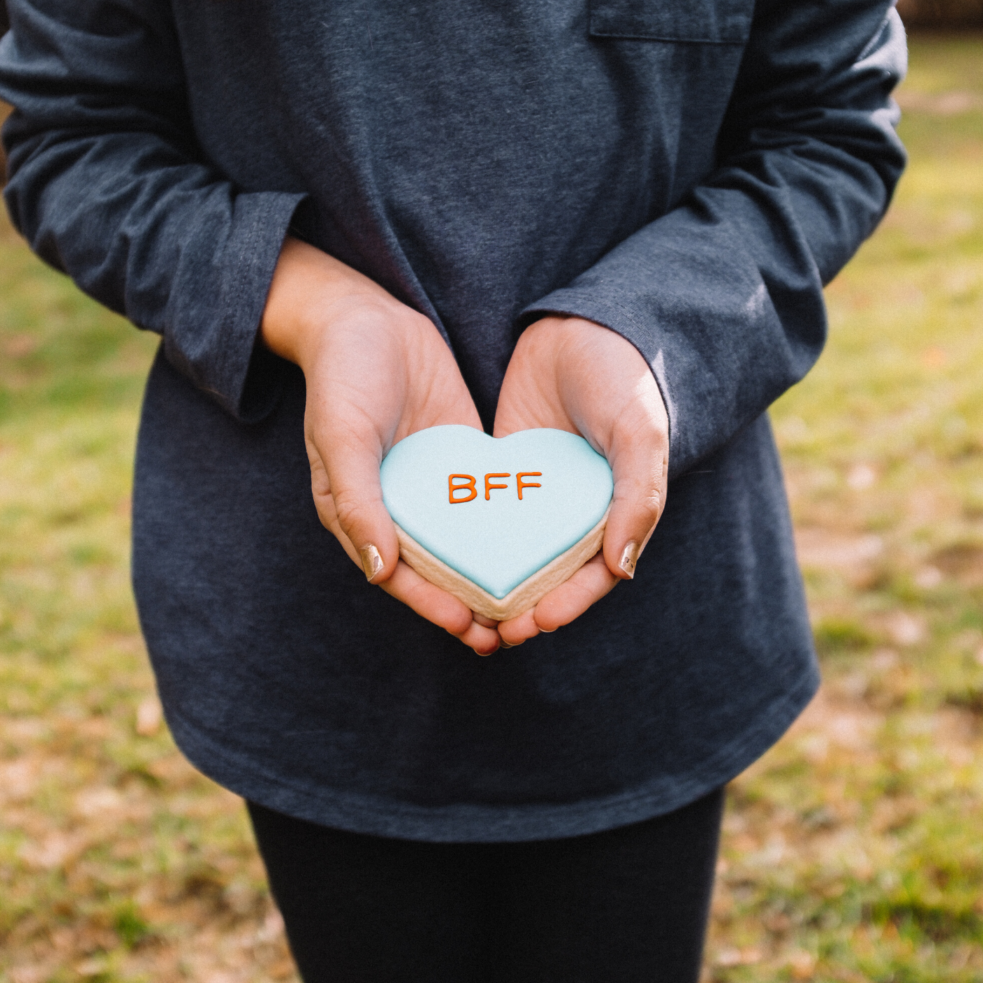 Lifestyle image of blue heart shaped cookie that says &quot;bff&quot;