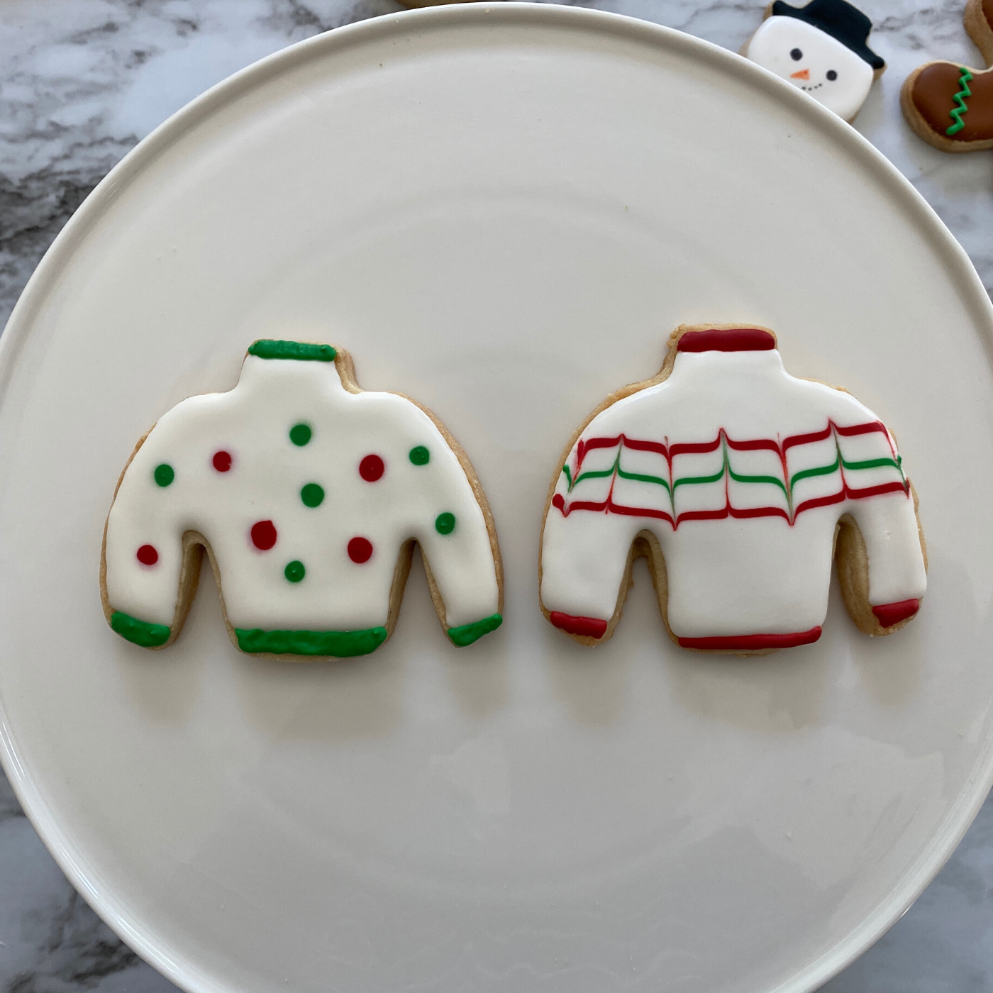 Lifestyle image of two completed Christmas sweater cookies 