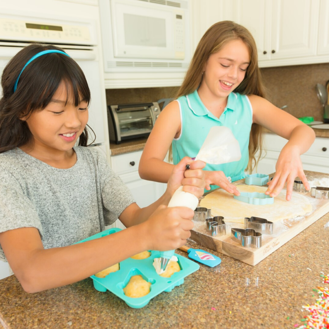 Lifestyle photo of children frosting ice cream shaped cupcakes and cutting ice cream shaped cookies