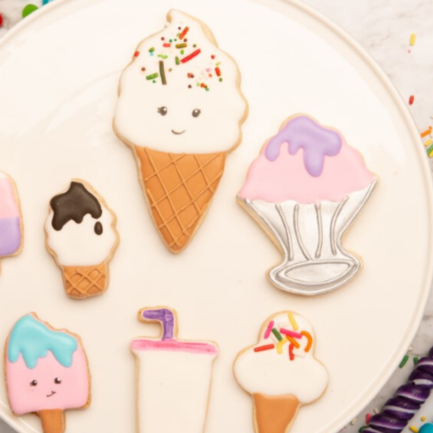 Ice cream cone and ice cream sundae shaped cookies decorated with colored frosting made using the Ice Cream Parlor Set of 2 Cookie Cutters