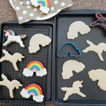 Lifestyle image of cut out cookies in the shape of unicorns and rainbows. \