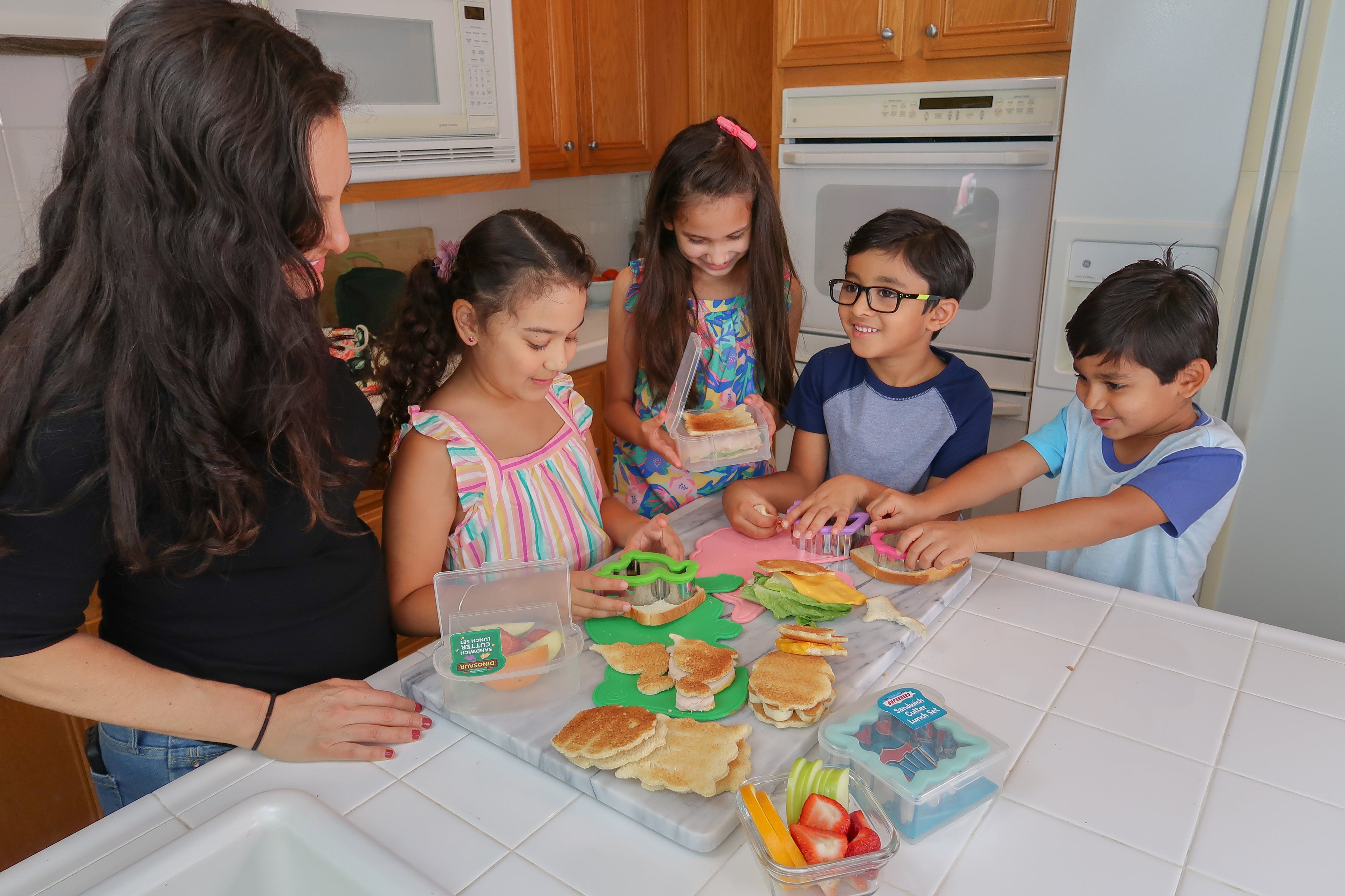 Lifestyle image of a family making sandwiches using the rainbows and unicorns cutter lunch set