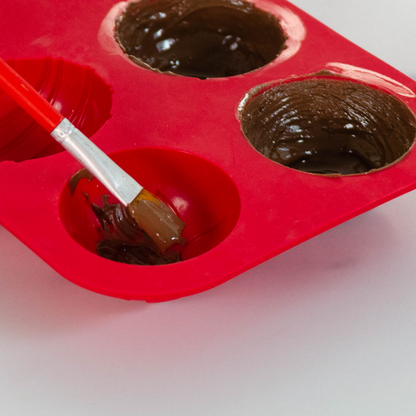 Lifestyle image shown &quot;painting&quot; melted chocolate onto the mold to create hot cocoa bomb spheres