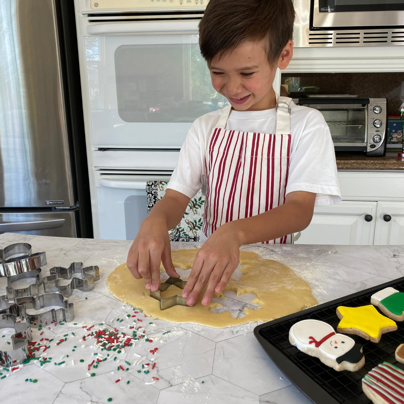 Lifestyle image of a child using the winter wonderland cookie cutter to cut out cookies 