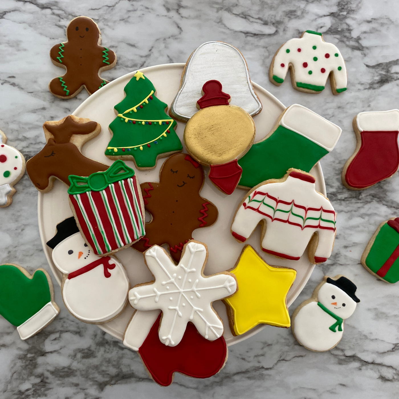 Lifestyle image of completed winter wonderland cookies including a snowman, Christmas tree, snowflake, and more.