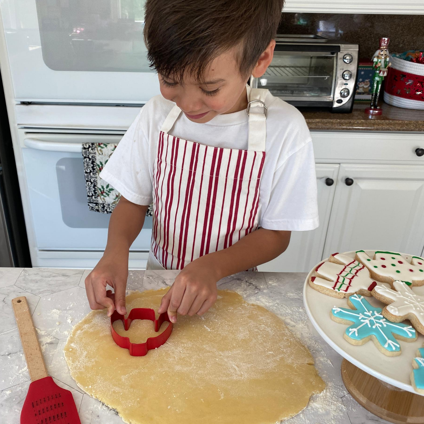 Lifestyle image of a child cutting out Christmas sweater cookies 