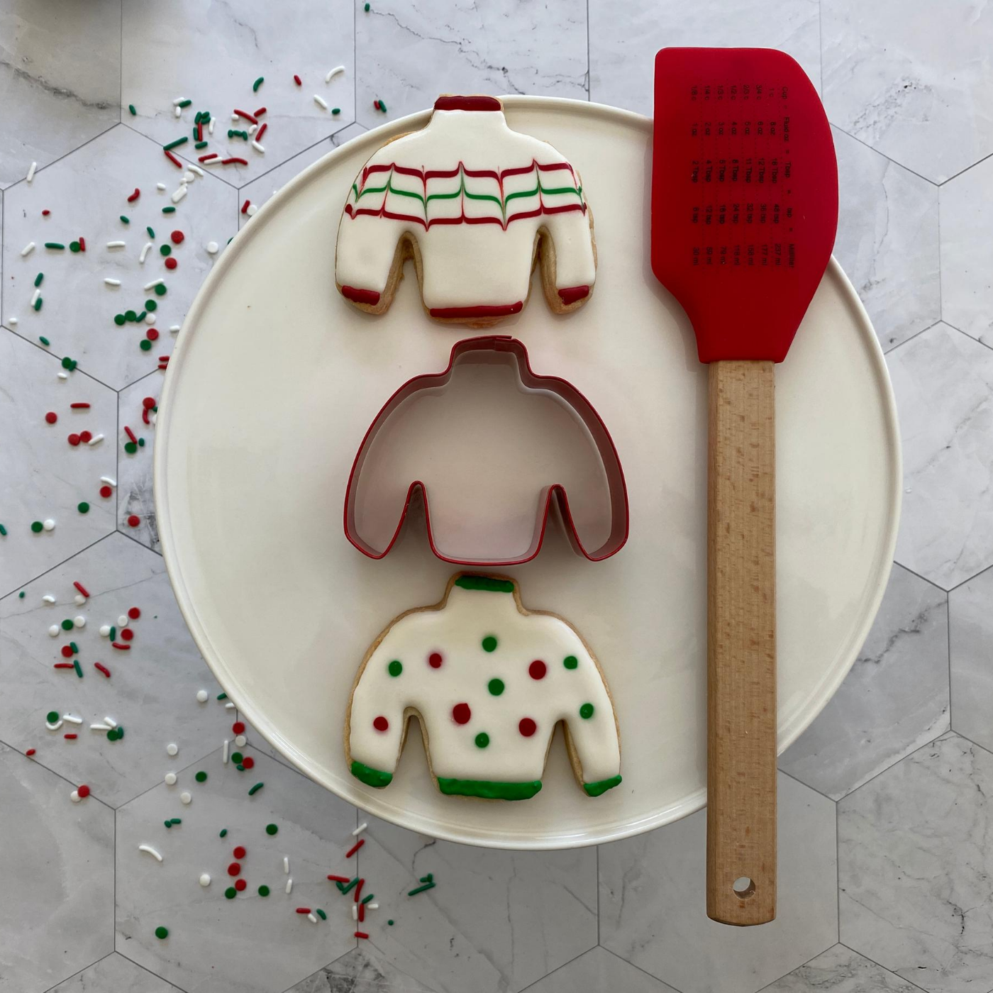 Image of 2 Christmas sweater cookies, one Christmas sweater cut out, and one Christmas spatula. 
