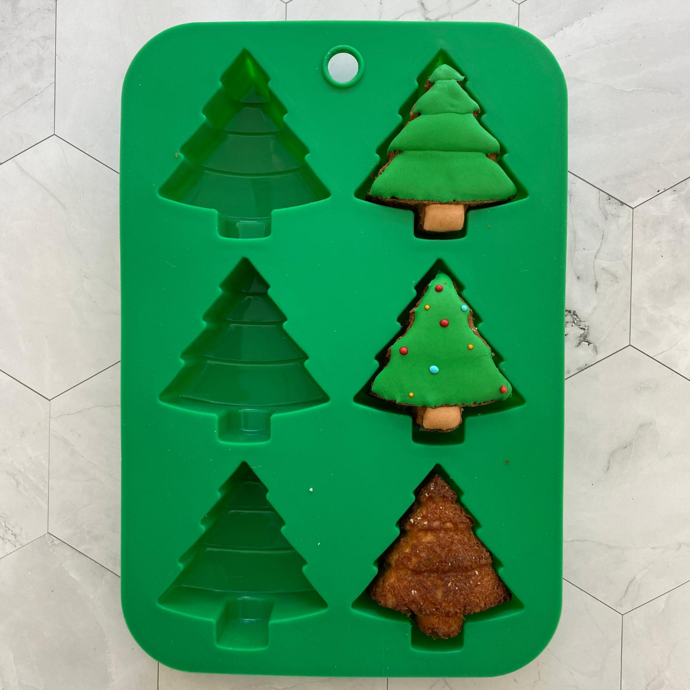 Image of the Winter Wonderland Holiday Tree Cupcake Mold with three completed cupcakes inside of the mold.